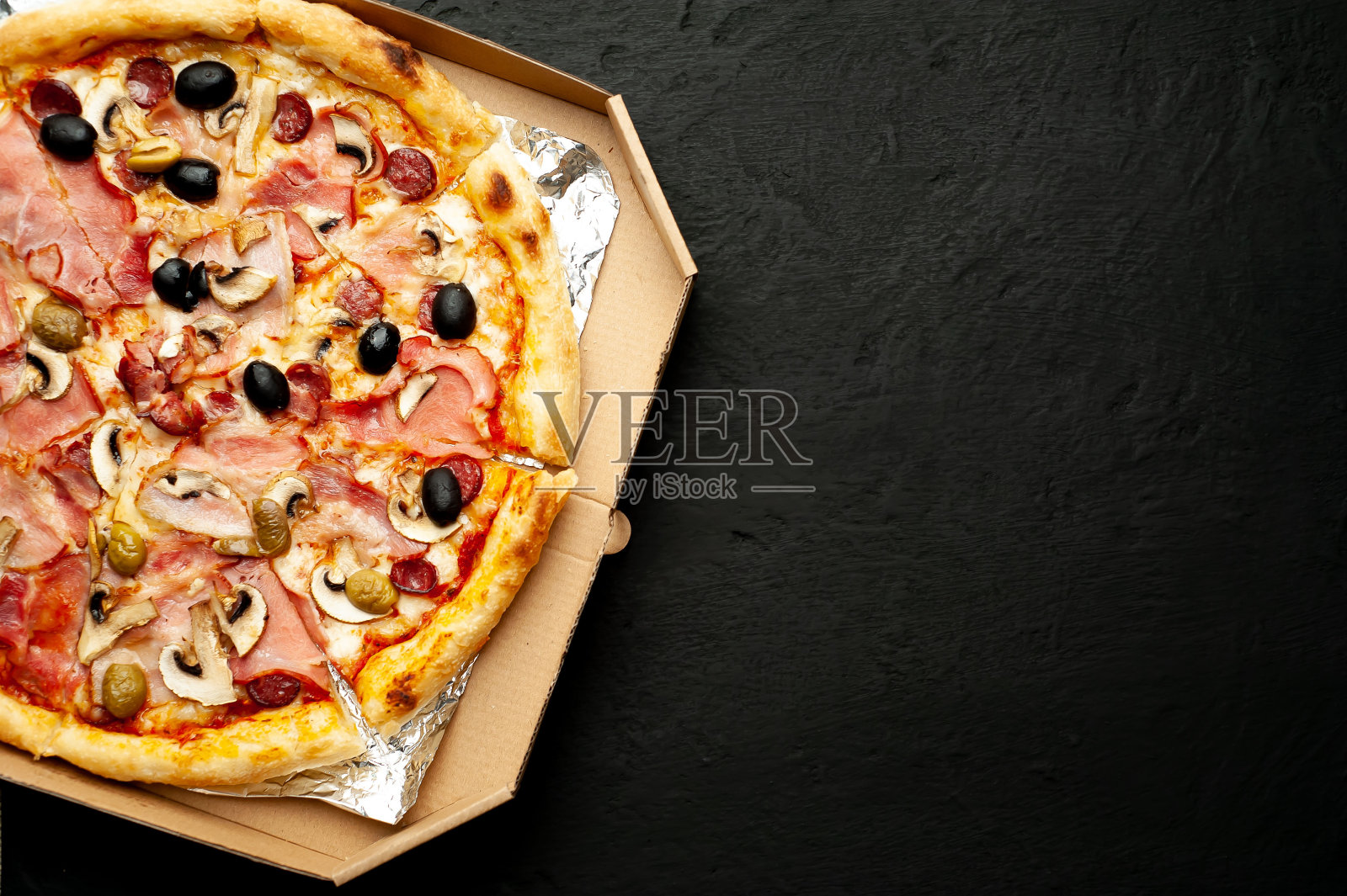 黑色混凝土背景下的美味披萨。热披萨俯视图。与复制空间的文本。照片摄影图片