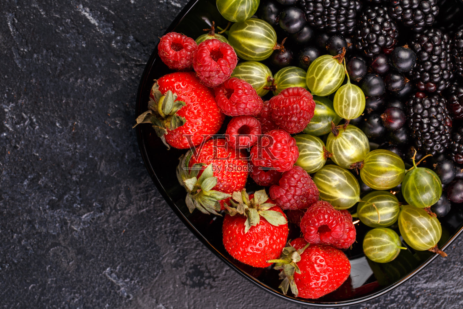 黑莓，草莓，覆盆子，醋栗放在黑色的盘子上照片摄影图片