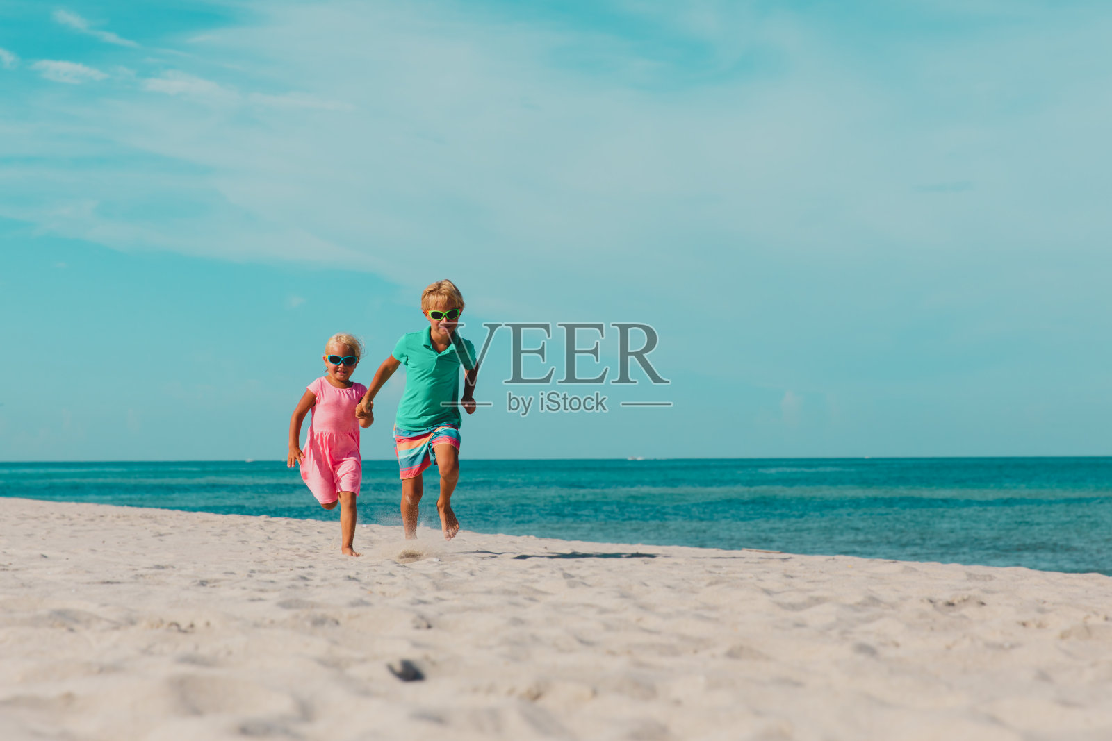 快乐的小男孩和小女孩在海滩上跑步照片摄影图片