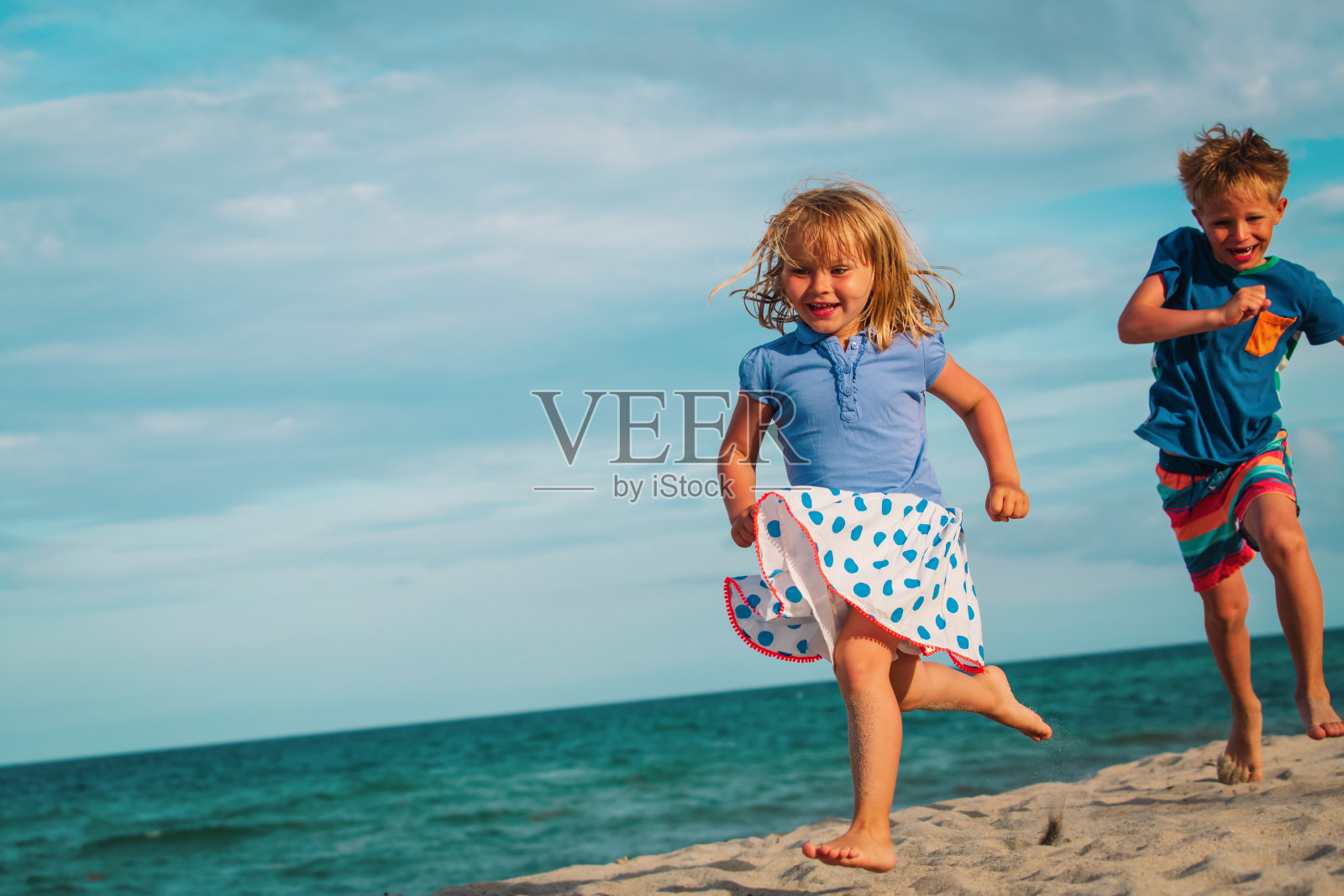 快乐的小男孩和小女孩在海滩上跑步照片摄影图片