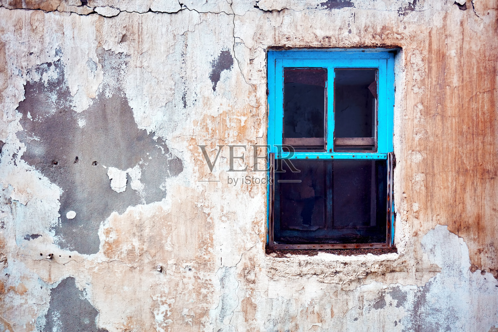 一个废弃的旧小屋的外观，蓝色的木窗框和破碎的墙壁照片摄影图片