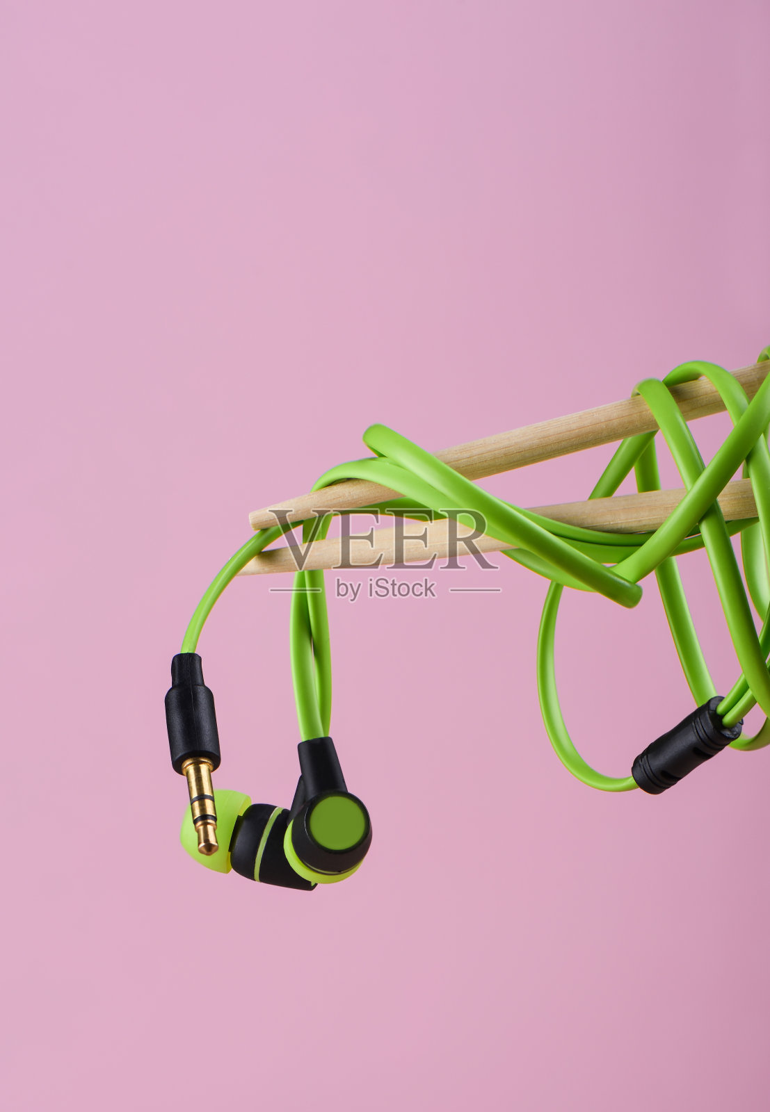 带有绿色耳机或耳机的筷子，隔离在粉红色背景上照片摄影图片