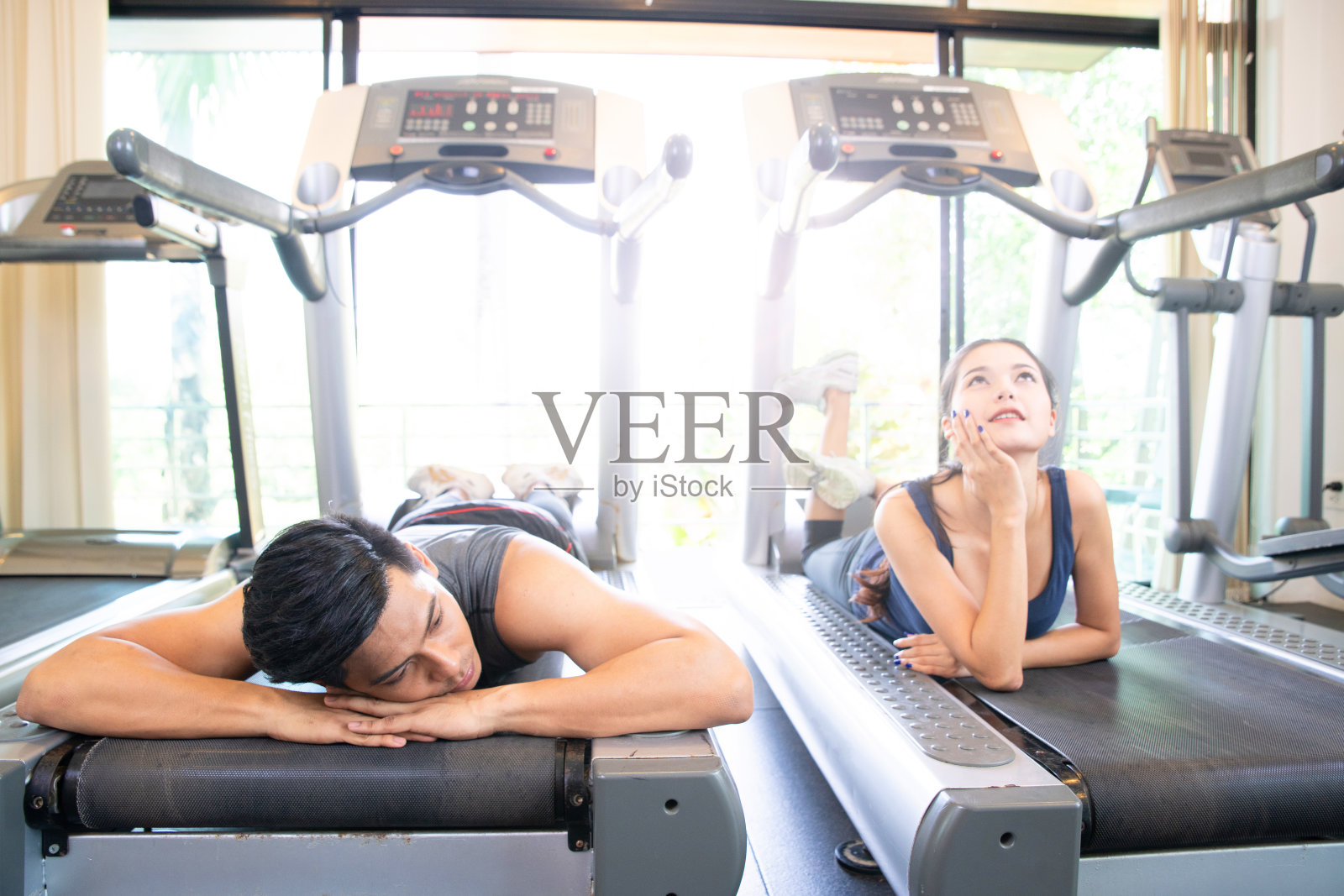 男人和女人在电动跑步机上慵懒地睡觉，懒人运动的概念照片摄影图片