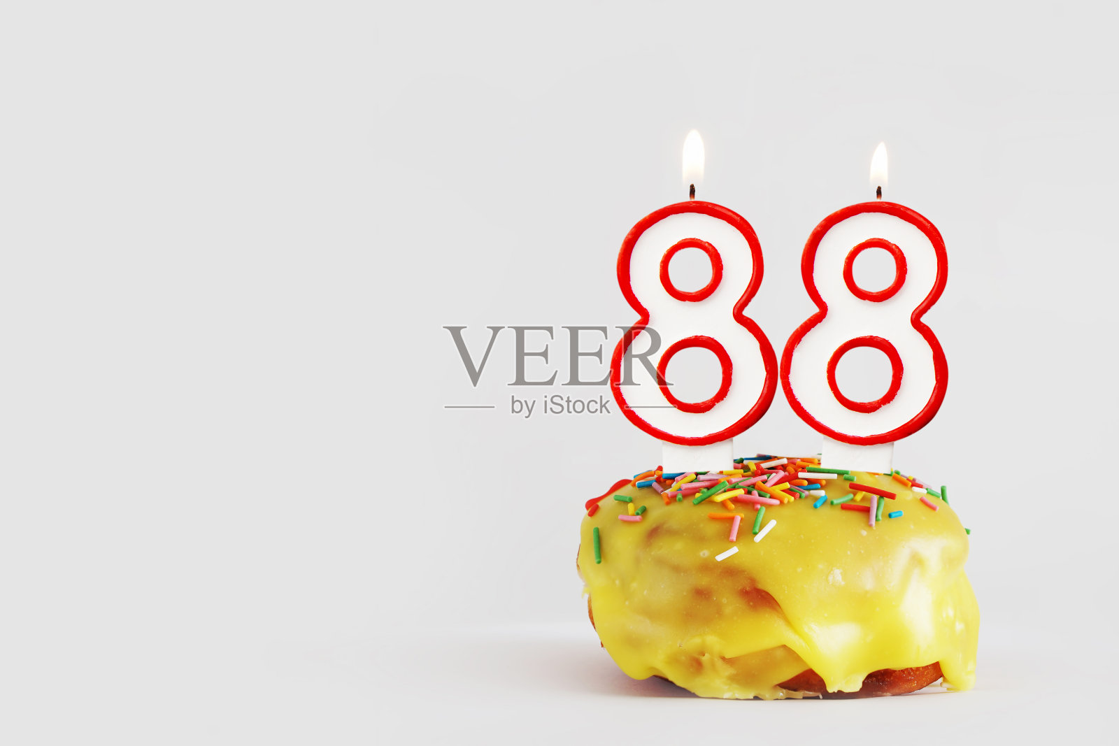 88周年纪念。生日纸杯蛋糕与白色燃烧的蜡烛与红色边框形式的88数字。浅灰色背景与复制空间照片摄影图片