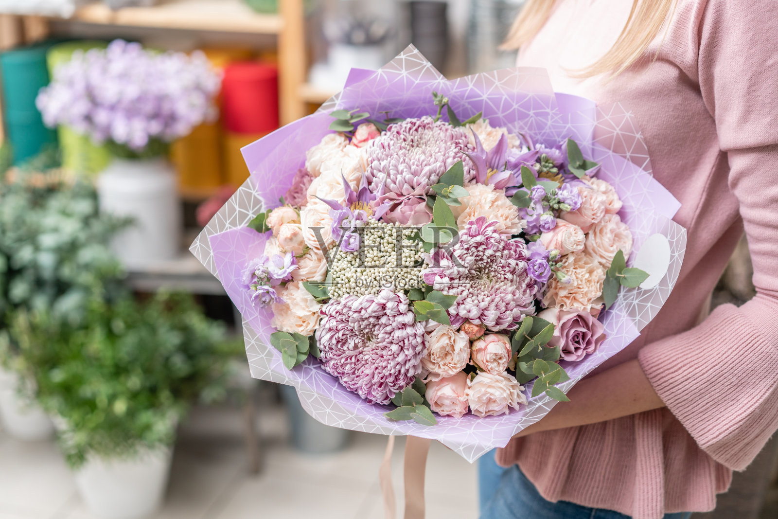 欧洲花卉商店。女人手里捧着一束美丽的混合鲜花。优秀的园林花卉在安排上，是专业花匠的工作。照片摄影图片