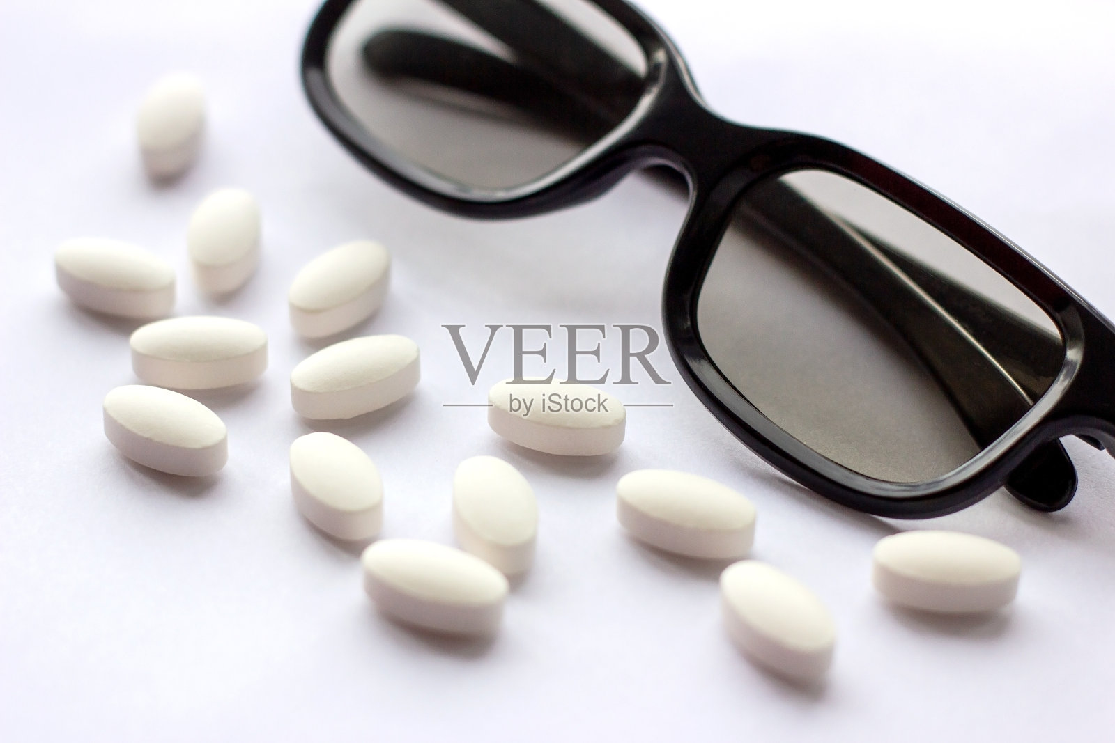 白色药丸和药片，带眼镜，背景亮。药学和医学概念。专注于眼科疾病的制药行业照片摄影图片