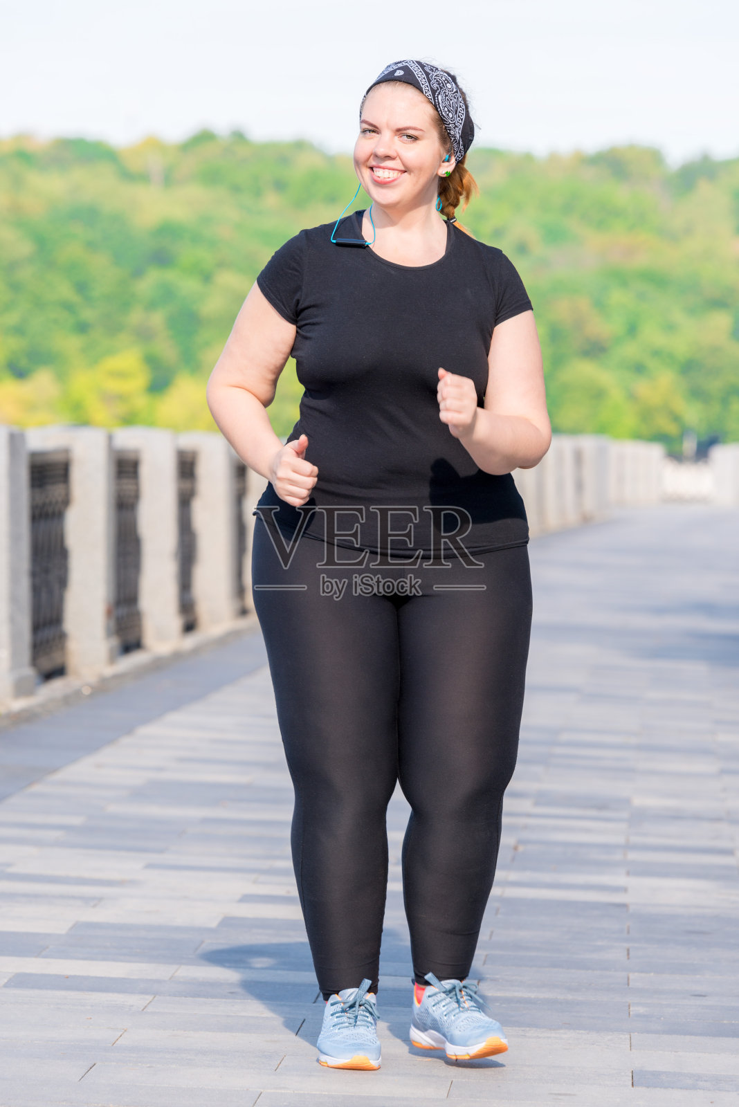 活跃的胖女人在城市公园晨跑，锻炼她的身材照片摄影图片