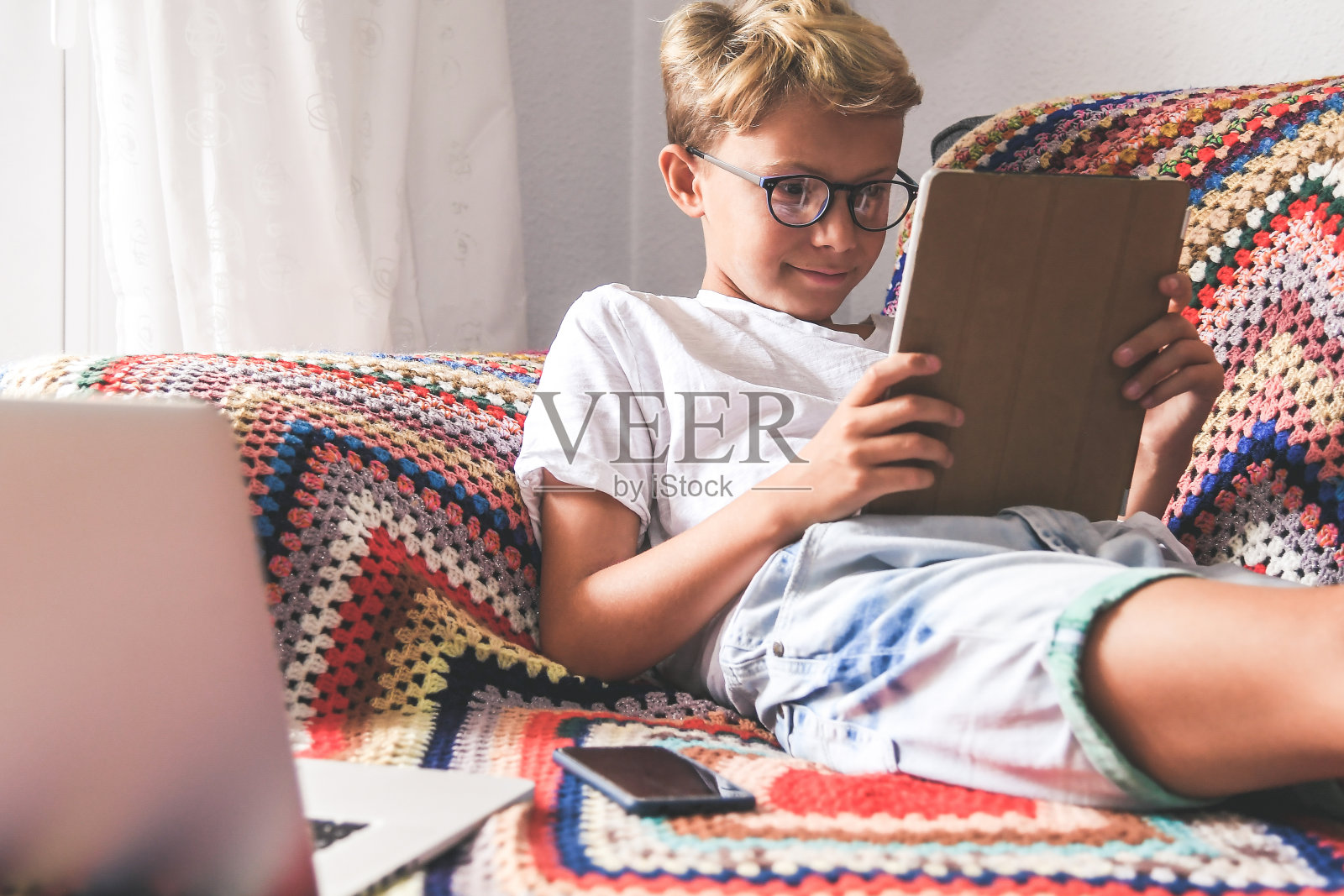 美丽微笑的青少年在平板电脑上阅读在线新潮流故事。沉迷于科技的小男孩在家看社交视频。青少年交流与z世代远程朋友青年科技理念照片摄影图片