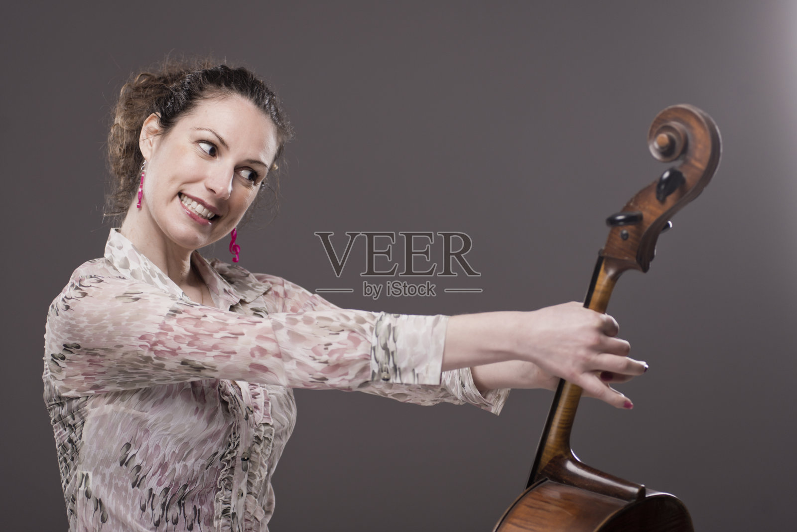 年轻的女大提琴手对她的大提琴很生气照片摄影图片
