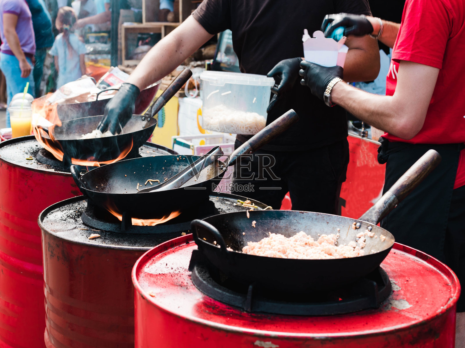 在街头节日用平底锅盛食物，用红桶生火。照片摄影图片