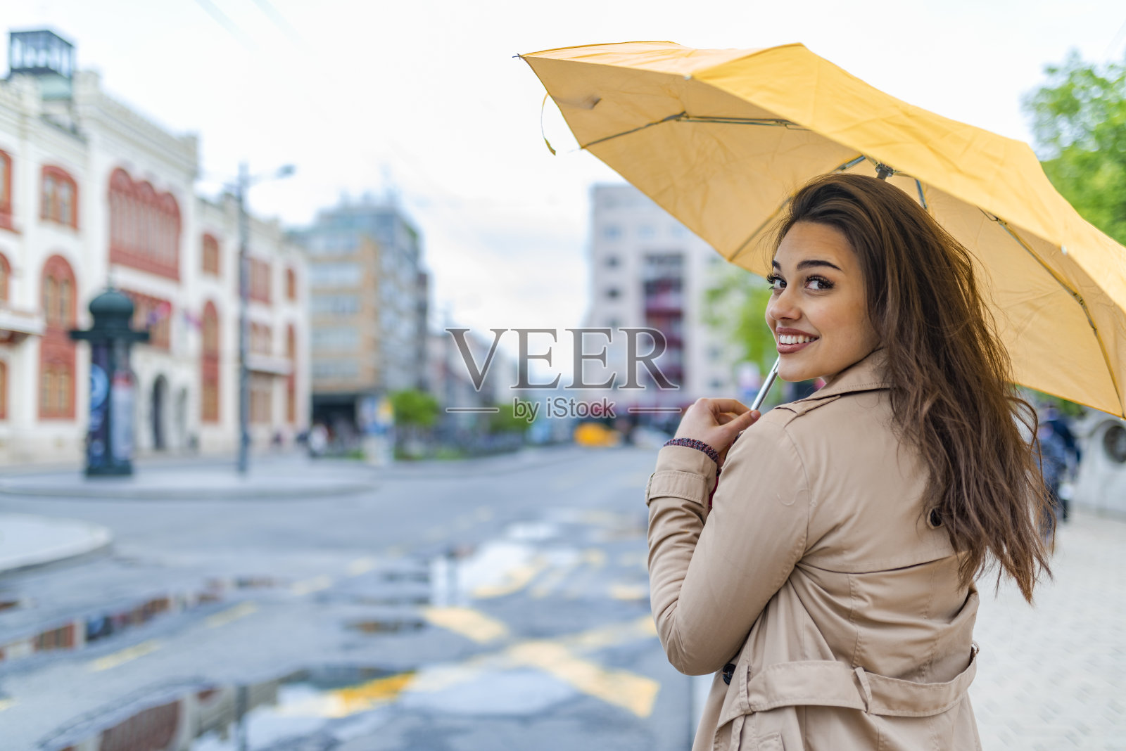 一个拿着黄色雨伞的女孩正在躲雨照片摄影图片