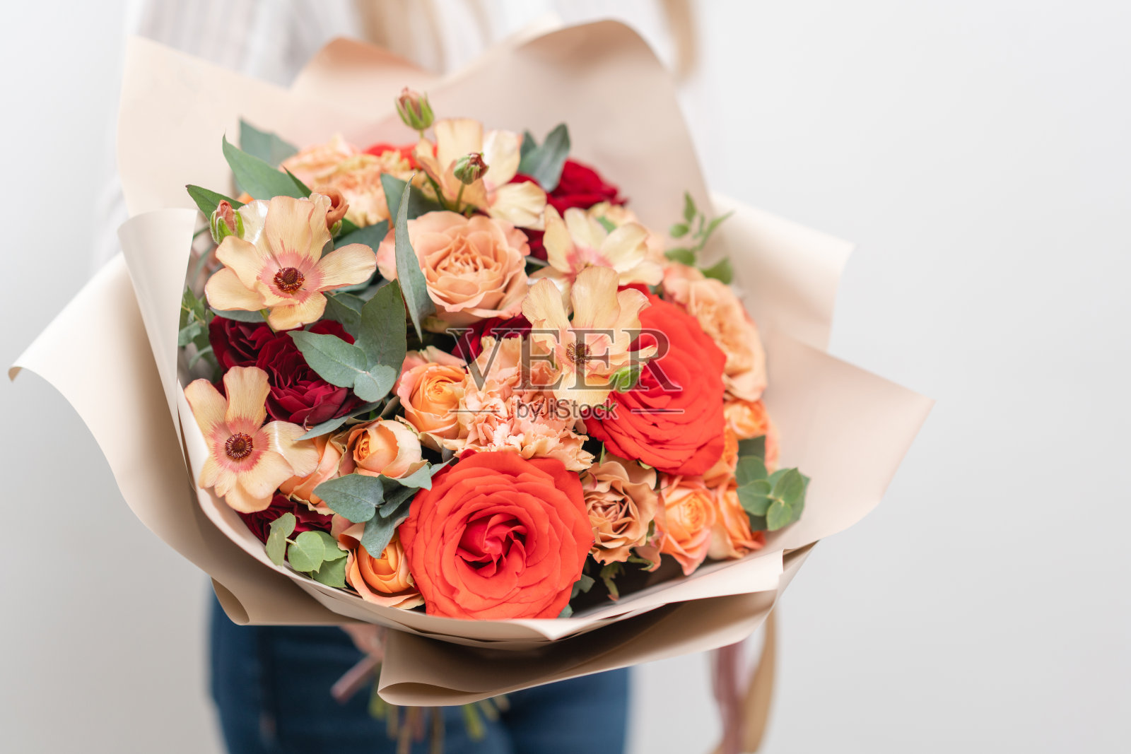 女人手里捧着一束美丽的混合鲜花。花店花匠的工作。精致柔和的颜色。新鲜切花。红色和桃红色照片摄影图片