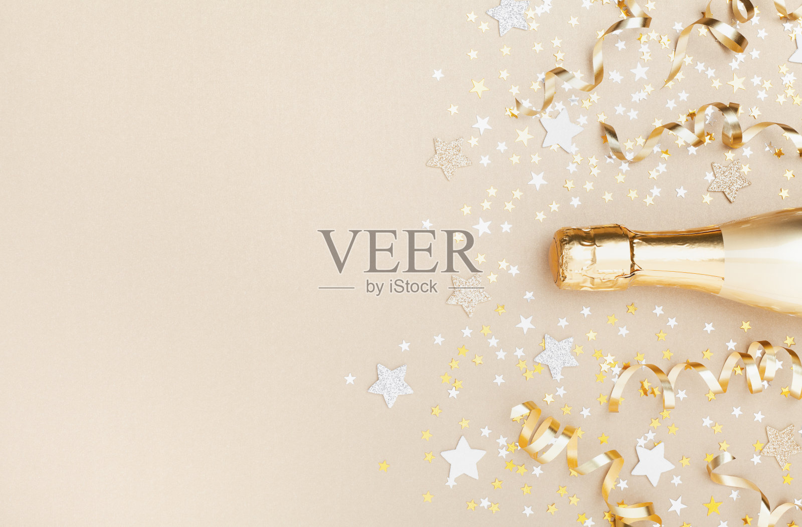 金色的香槟酒瓶上有星星和派对彩带俯视图。圣诞节、生日或婚礼背景。平的。照片摄影图片