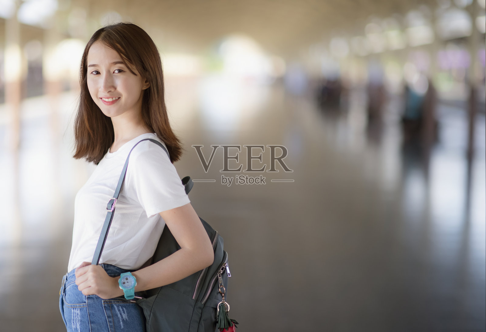 一个亚洲女人背着一个背包，微笑着看着旁边照片摄影图片