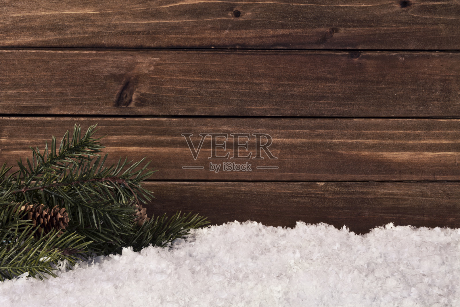 圣诞树的树枝和雪在一个天然木板的背景。照片摄影图片