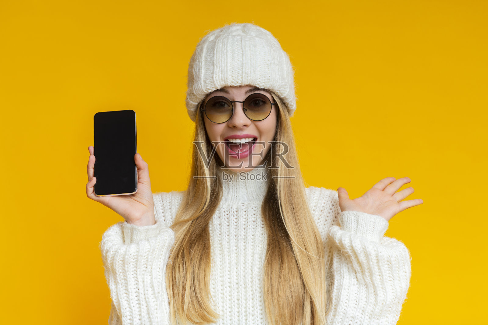 情绪化的女人在冬季帽子展示空白的智能手机屏幕照片摄影图片