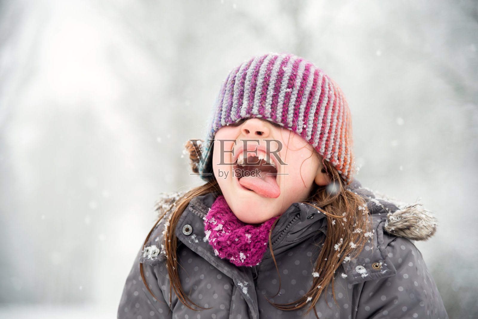 小女孩在雪中玩耍，她试图用她的嘴去接雪花照片摄影图片