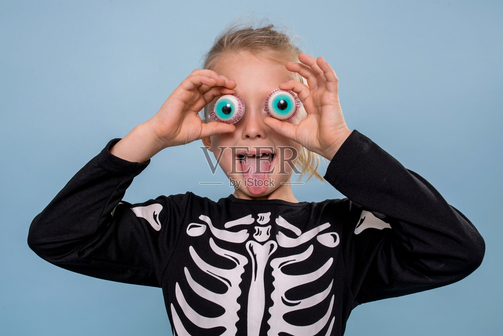 穿着骷髅装的小男孩在眼皮上拿着可怕的玩具眼球照片摄影图片