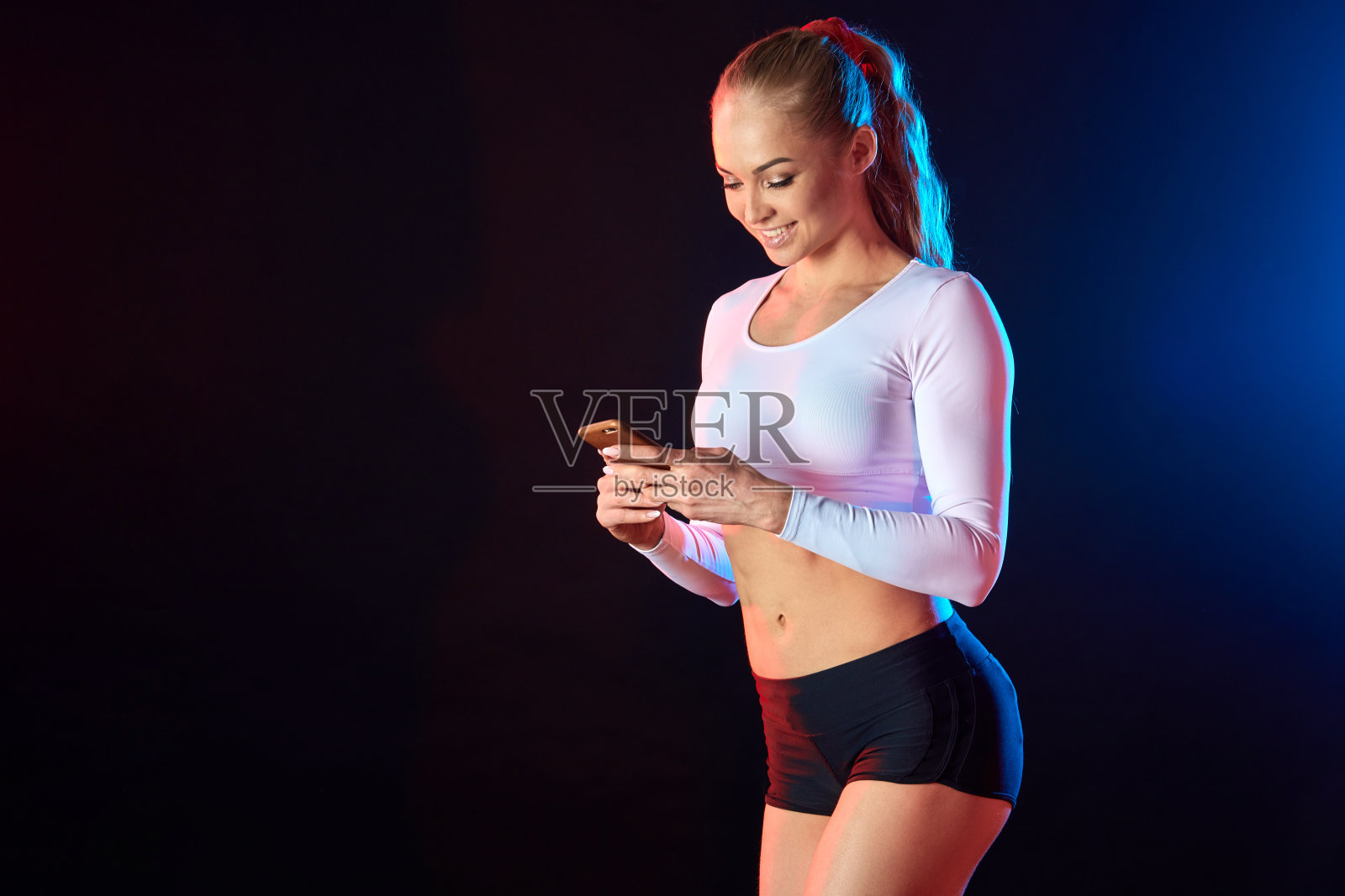 一个快乐的健身女孩的肖像使用手机孤立的黑色背景照片摄影图片