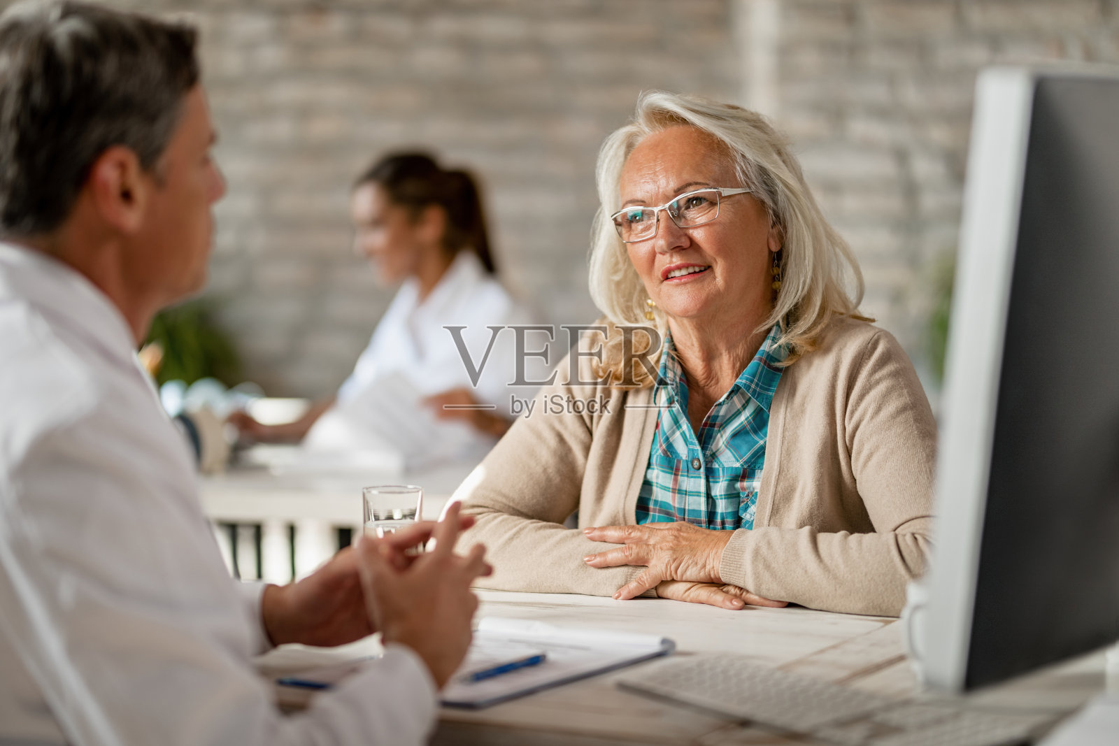 微笑成熟的女人有一个咨询与保健工作者在诊所。照片摄影图片