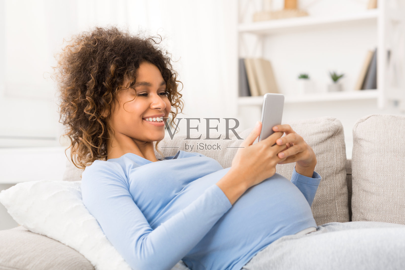 快乐的孕妇在用智能手机上网照片摄影图片