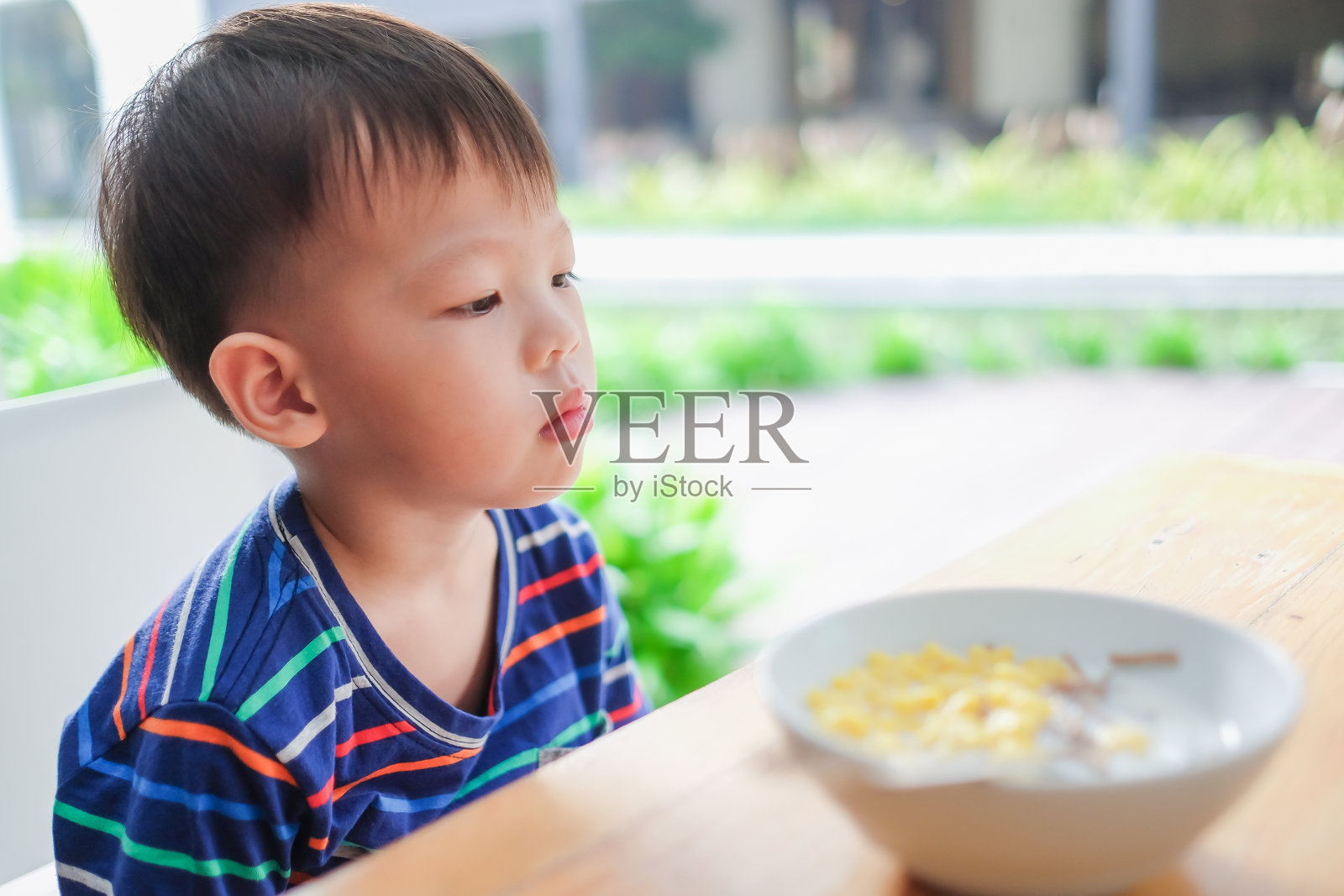 亚洲3 - 4岁蹒跚学步的男孩穿着条纹t恤拒绝进食照片摄影图片