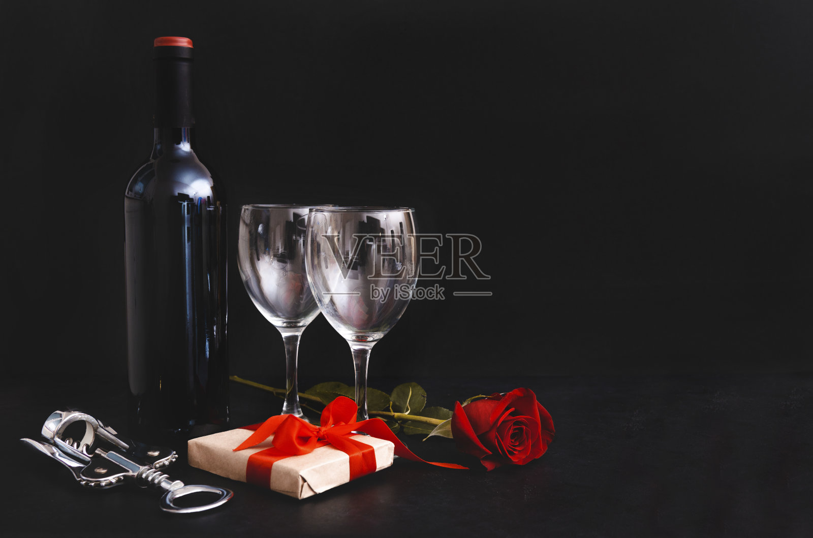 一瓶葡萄酒，2杯，黑葡萄，开瓶器，红玫瑰，礼盒与黑色背景缎带，复制空间照片摄影图片