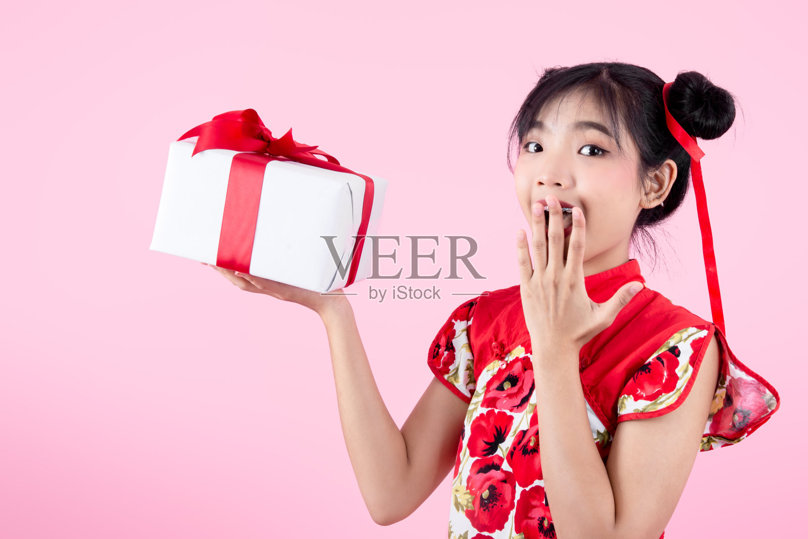 快乐的亚洲少女穿着旗袍传统红裙拿着礼盒为2020年中国新年孤立上粉红色。照片摄影图片