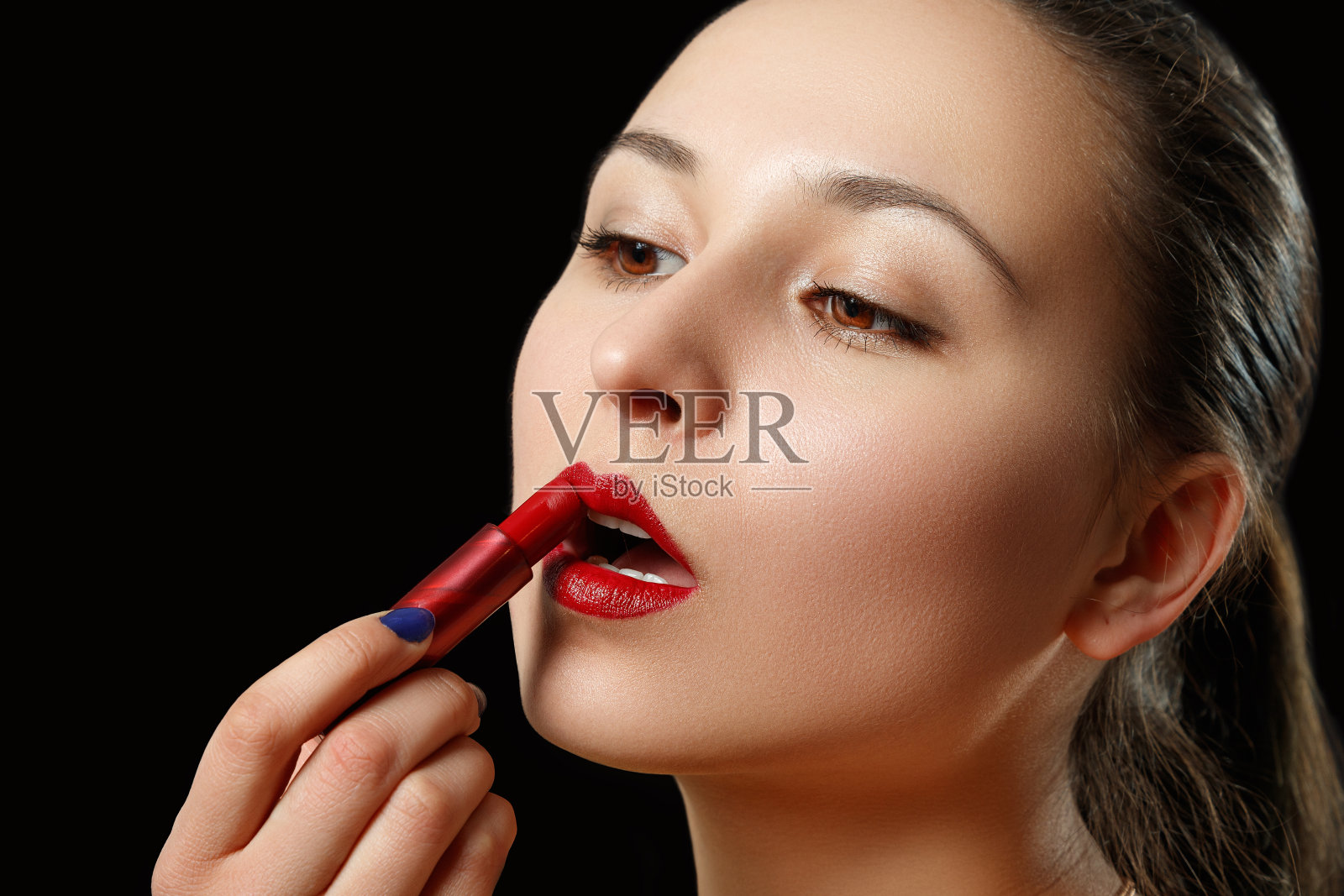 一个女人用红色的口红涂她的嘴唇照片摄影图片