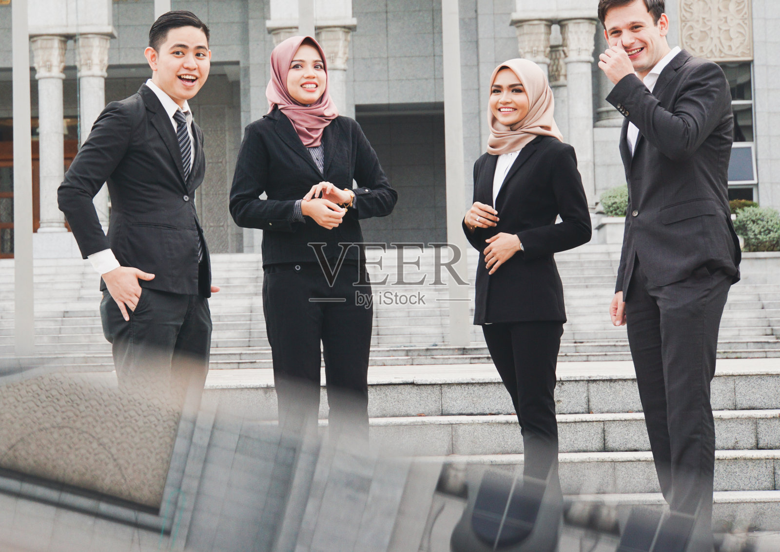 一群聪明的亚洲职业男女聚集在办公大楼外，看上去既专业又时髦。照片摄影图片