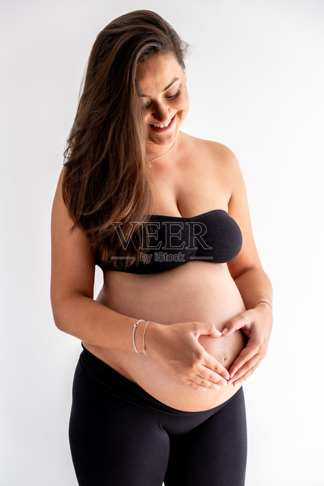 一名孕妇把手放在肚子上做出了一个心形的形状照片摄影图片
