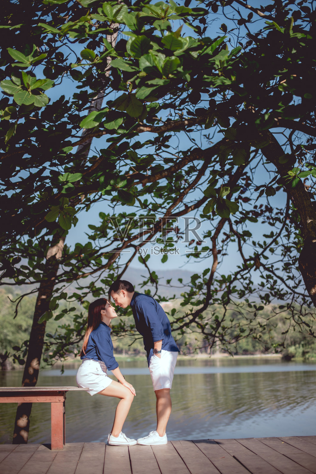 这对亚洲情侣将在湖边的公园里一起接吻。照片摄影图片