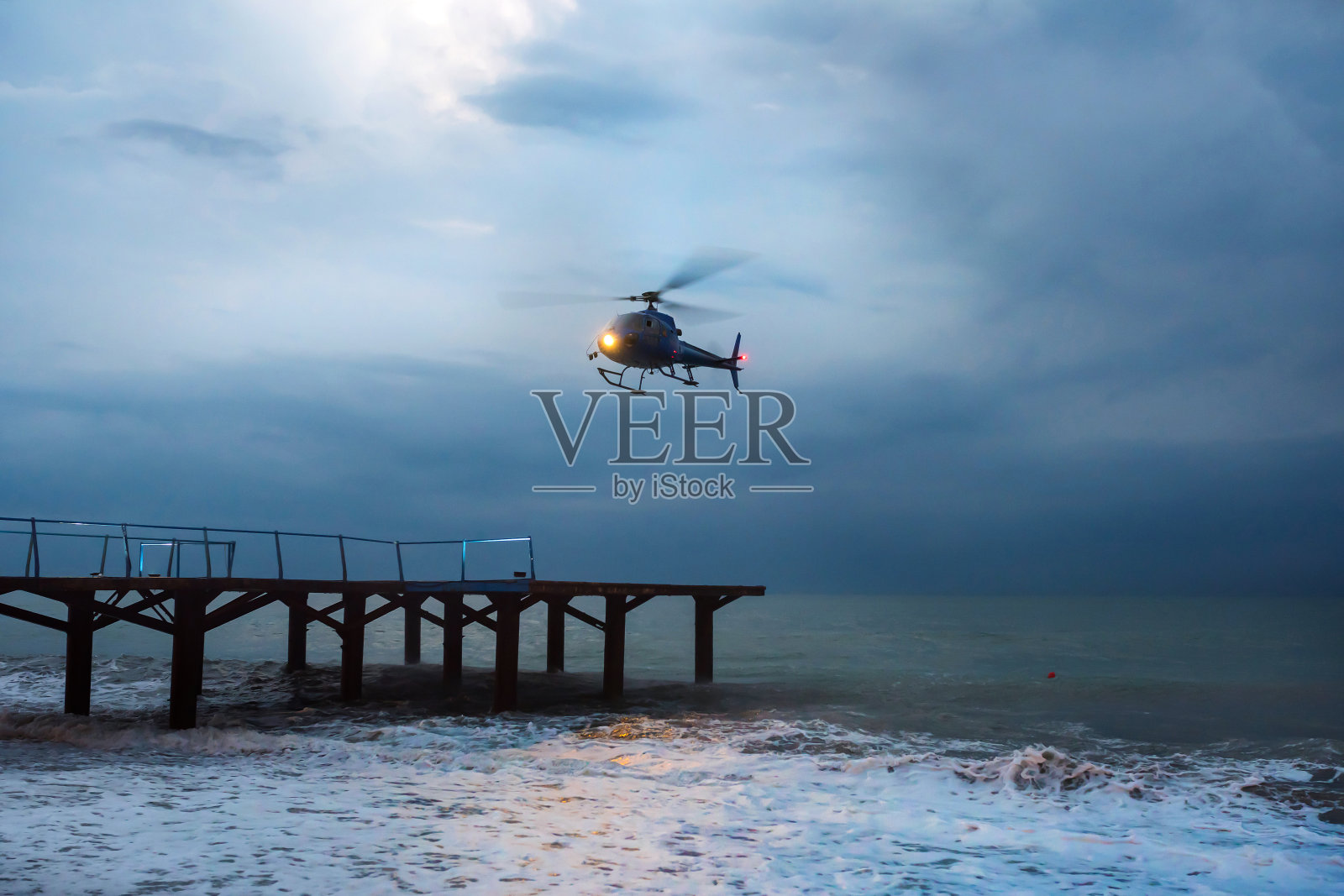 一架直升飞机在暴风雨中起飞。照片摄影图片
