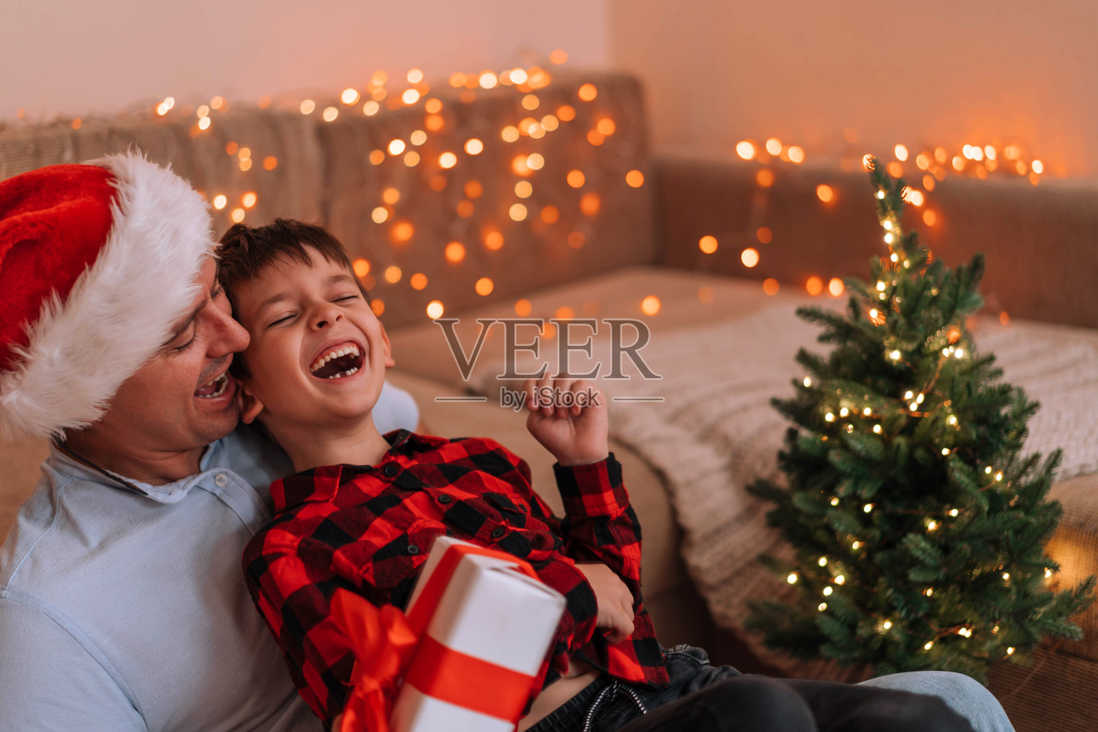 爸爸和儿子在新年过节带着礼物笑。照片摄影图片