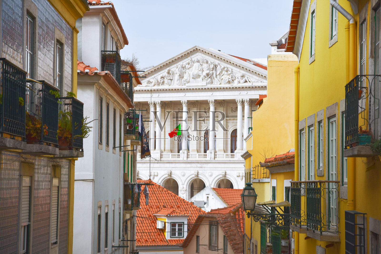 夏日阳光明媚的Travessa da Arrochela大街上五颜六色的老建筑阳台。共和国大厦的背景。旅行的概念。葡萄牙里斯本。欧洲照片摄影图片