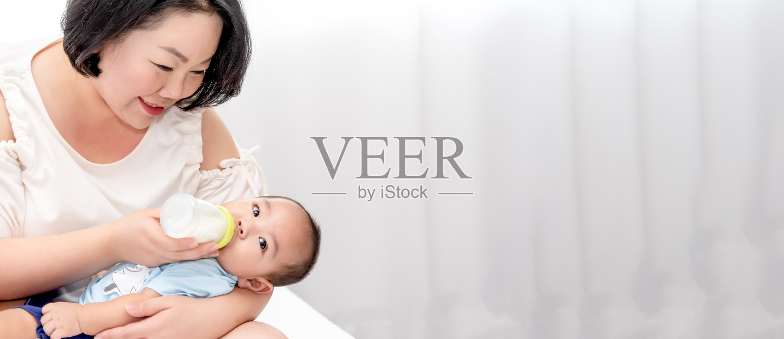 亚洲母亲给5个月大的男婴喂奶。单身母亲或母亲节的概念。照片摄影图片