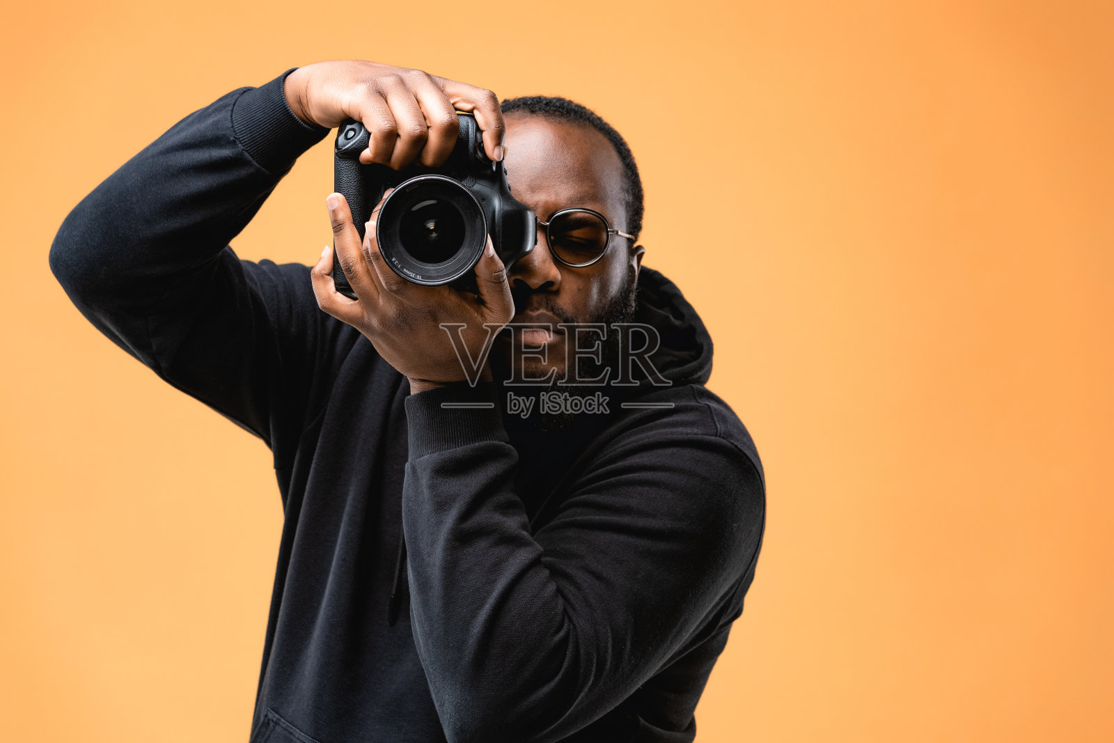 蓄着胡须的非裔美国专业摄影师职员在工作室里戴着眼镜。照片摄影图片