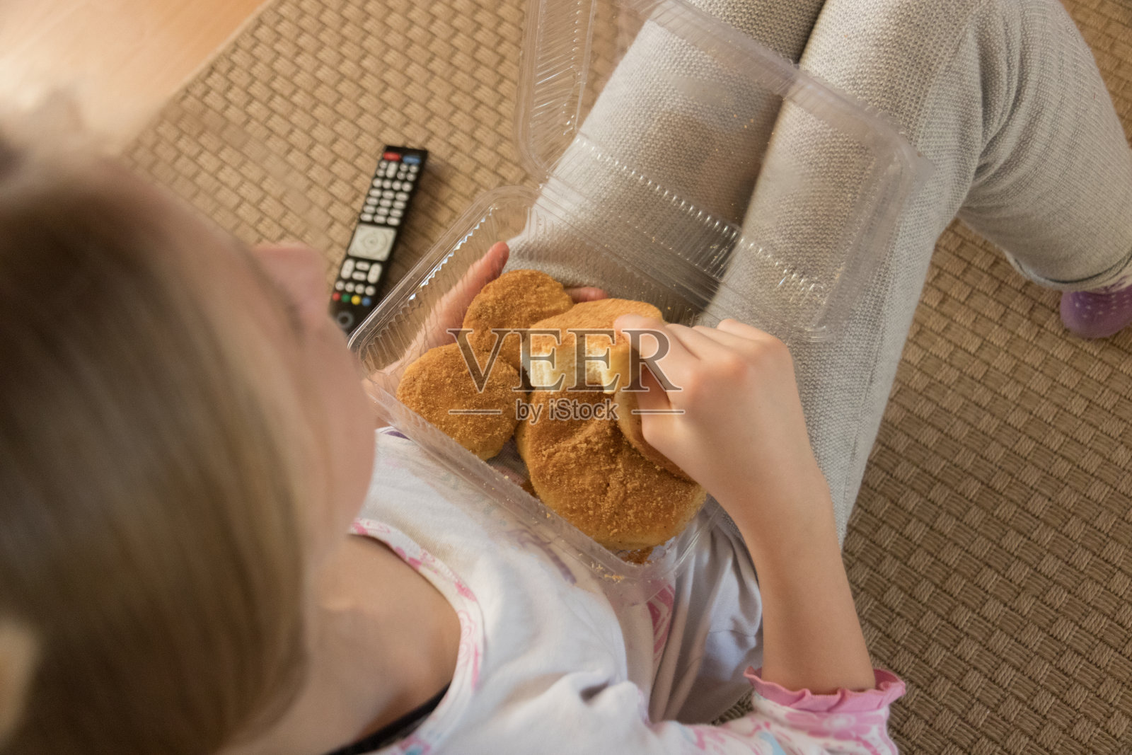 年轻的女孩正在她的客厅地板上看电视，吃着早餐放松。照片摄影图片