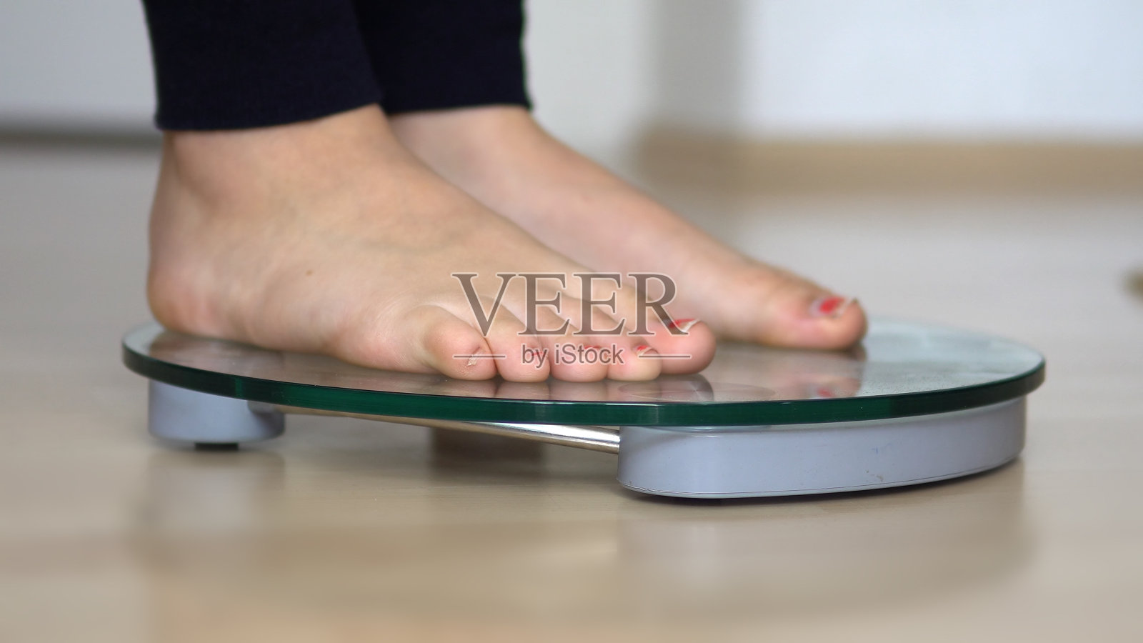 女性光脚配体重秤在木地板上，减肥节食照片摄影图片