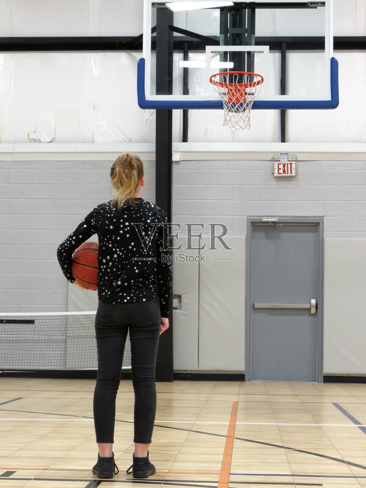女孩抱着篮球站在篮球网前照片摄影图片