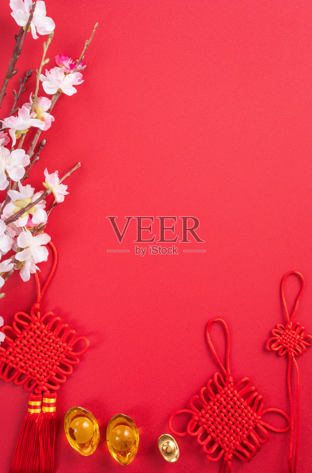 中国农历新年的设计理念-美丽的中国结与梅花孤立在红色的背景。照片摄影图片