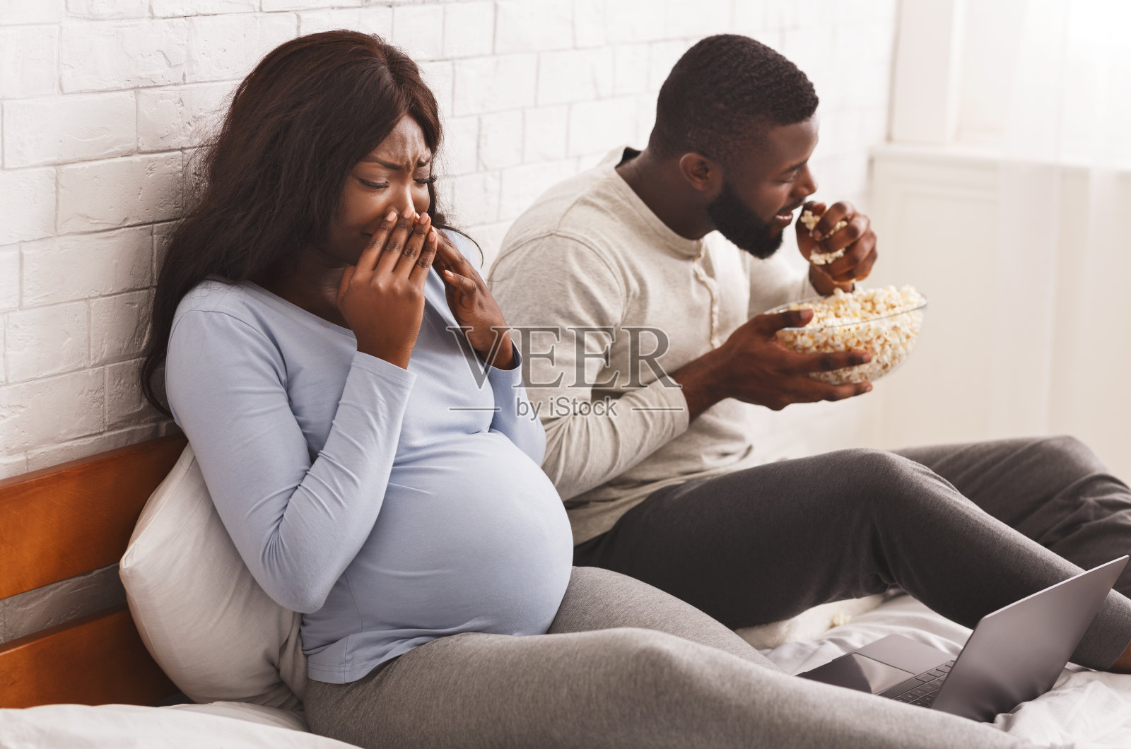 一个黑人在吃爆米花，而孕妇却背对着我照片摄影图片