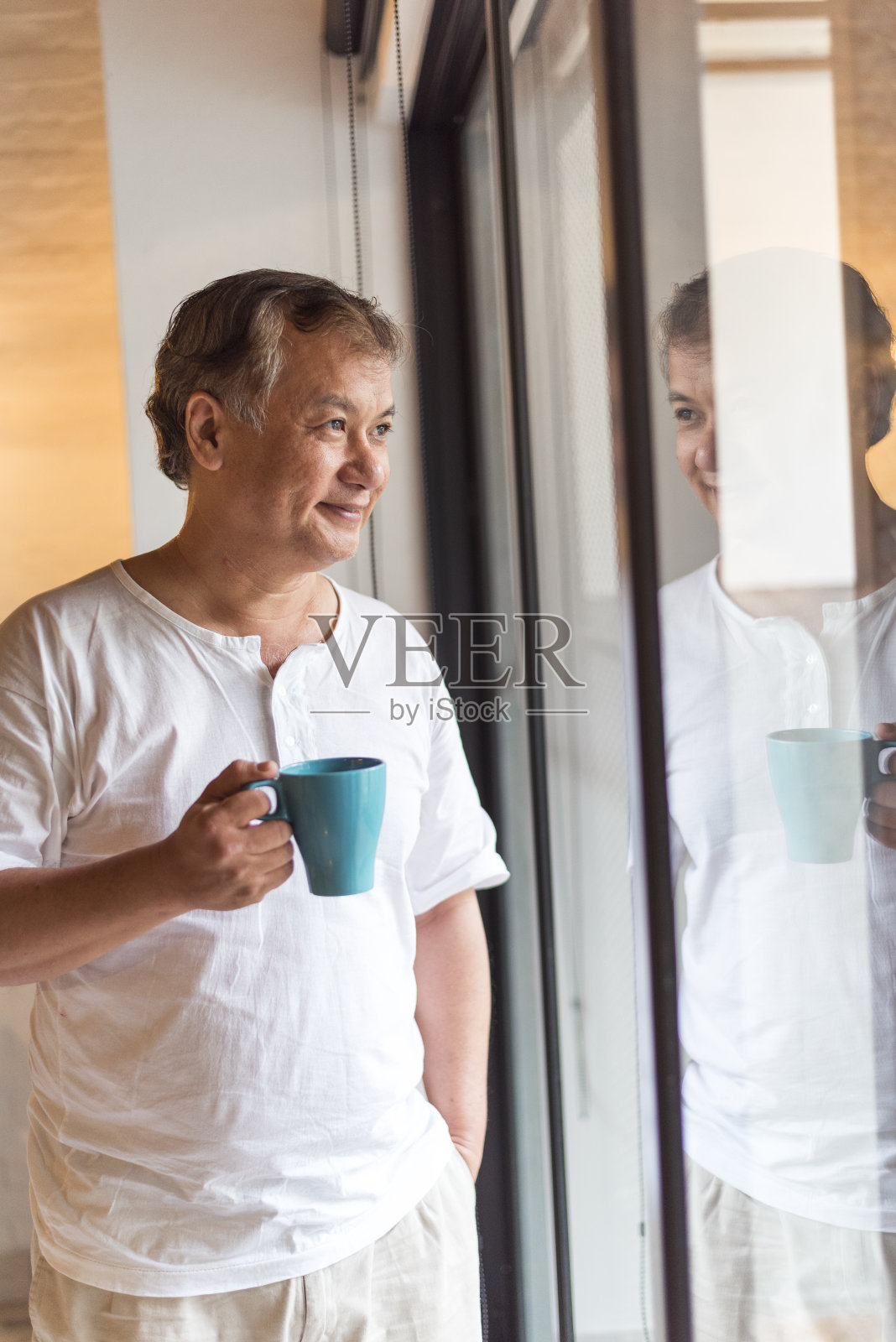 年长的亚洲人透过窗户看，喝着咖啡照片摄影图片