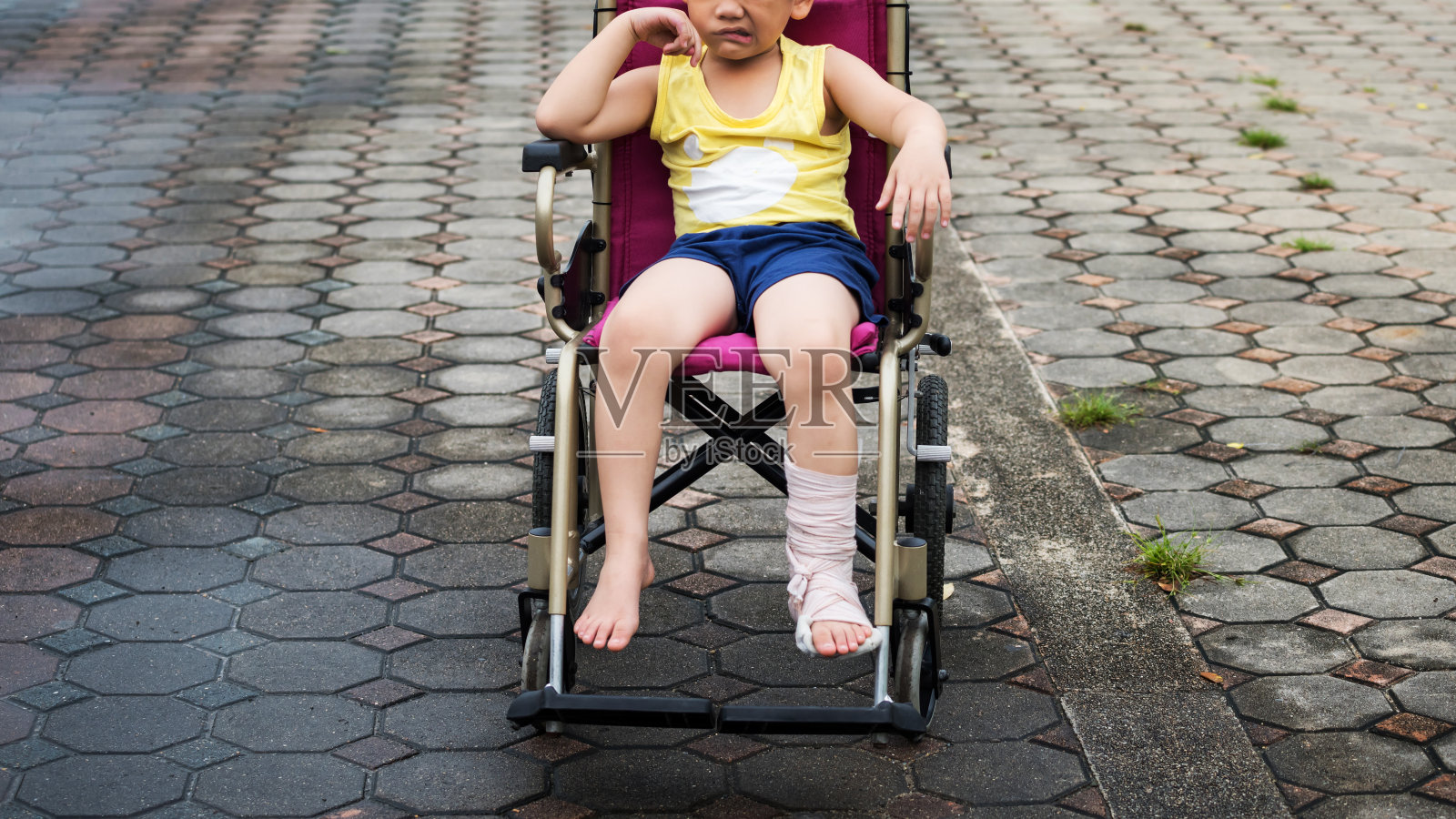 可怜的男孩，腿断了，在轮椅上打了石膏照片摄影图片