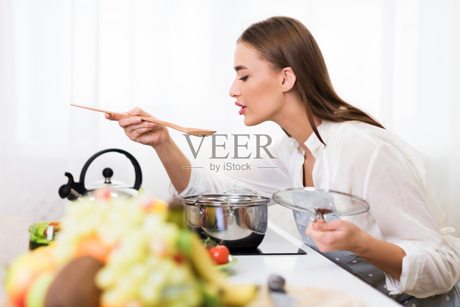 千禧一代的女人用勺子煮和品尝汤照片摄影图片