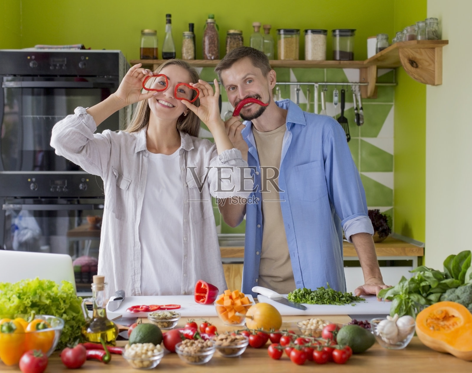 快乐的千禧夫妇享受新鲜辣椒和烹饪的乐趣照片摄影图片