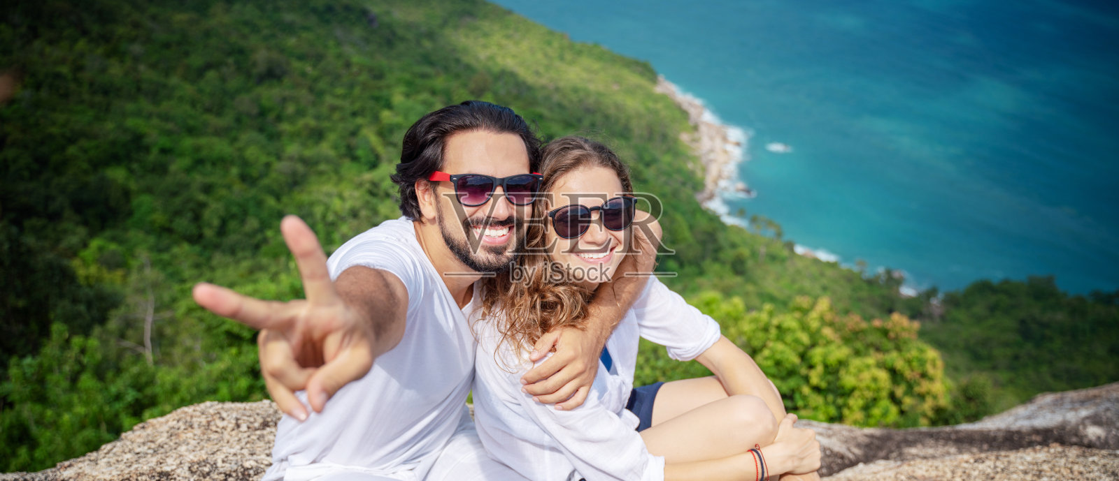 一对快乐美丽的年轻夫妇，一男一女，在山顶上有海景。浪漫的旅行,蜜月照片摄影图片