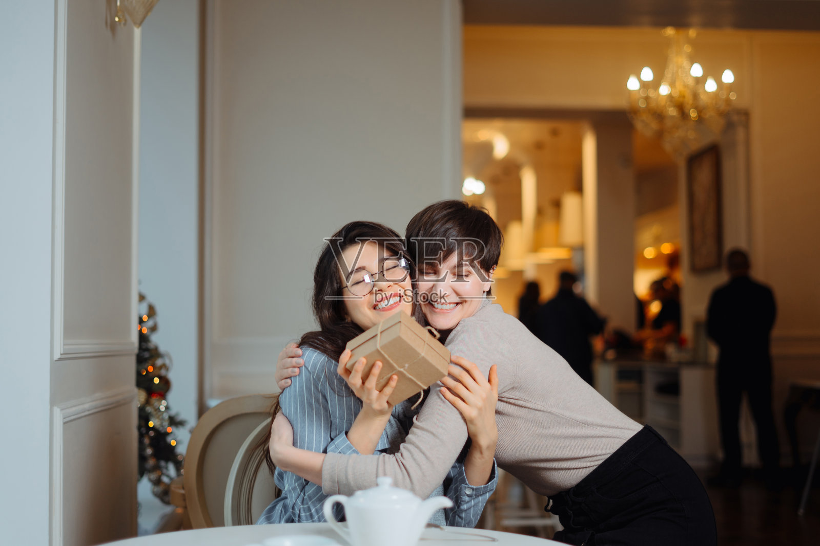 年轻美丽的女孩坐在咖啡馆和她的朋友，并接受一份礼物照片摄影图片