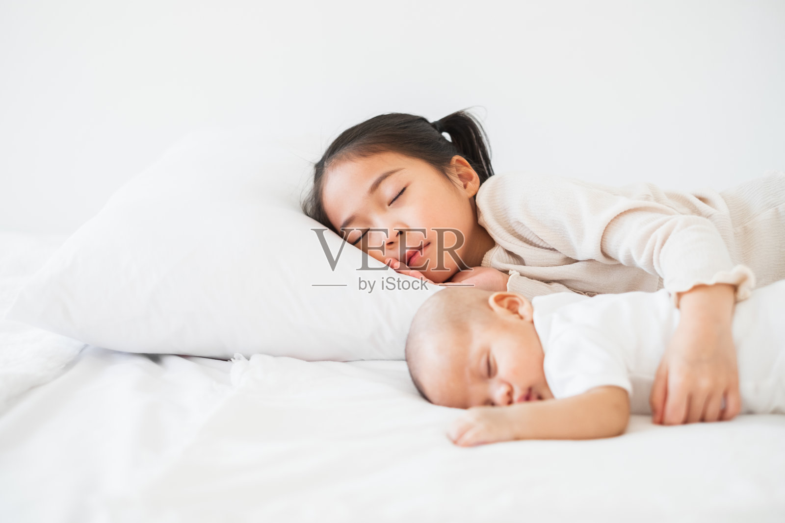 亚洲可爱的女孩和婴儿睡在白色的床上照片摄影图片