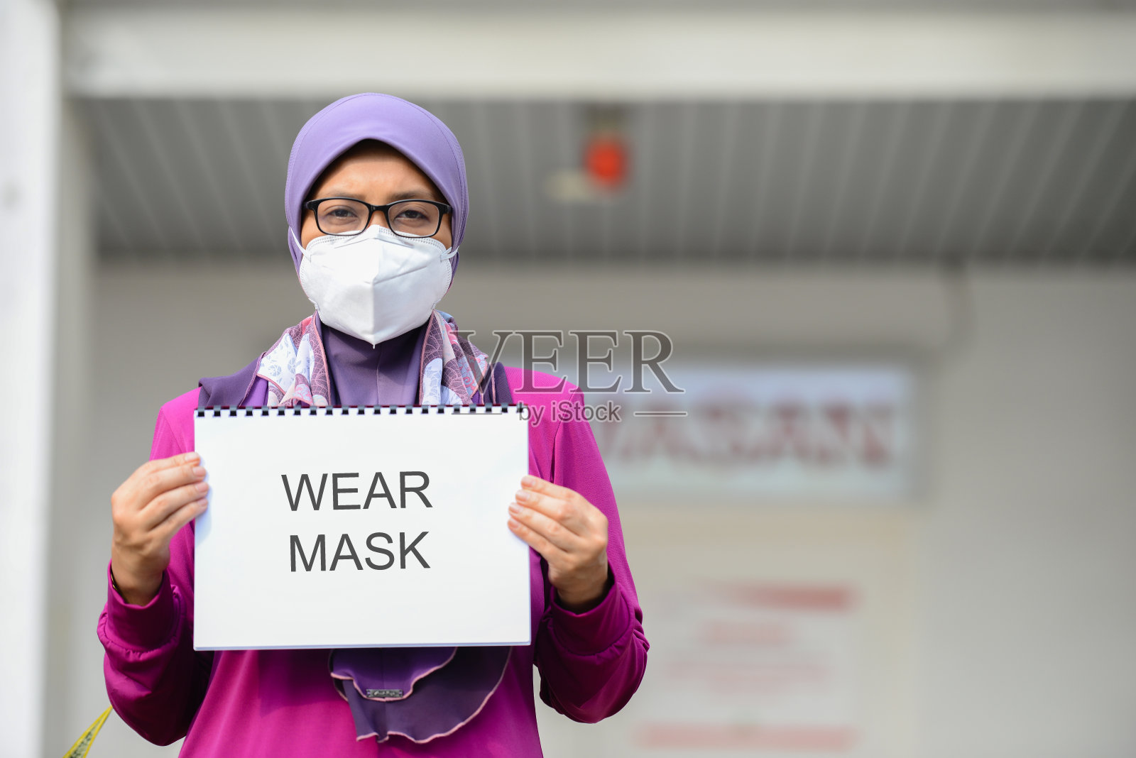 马来西亚医院前，医护人员戴着口罩举着标语照片摄影图片